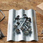 Fotografía comparativa de tres tipos de clavos CORVI: clavos de acero templado oscuros para concreto (con uno corriente doblado al lado), clavos de zinc con cabeza de paragua y sello sobre una lámina metálica, y clavos corrientes brillantes para madera.