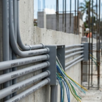 Tuberías de PVC eléctrico gris CORVI SCH 40 con certificación UL 651 instaladas en un muro de concreto durante una obra.
